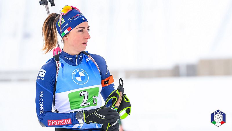 丽莎-维托兹（Lisa Vittozzi）带着滑雪设备站在雪地里。